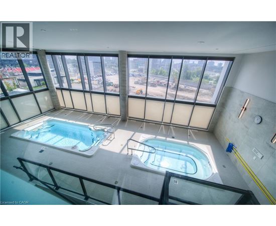 A large indoor swimming pool with a view of the city outside the windows.