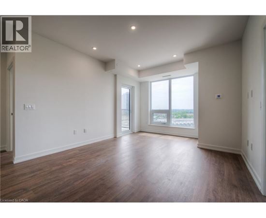 A spacious room with wooden floors and a large window.