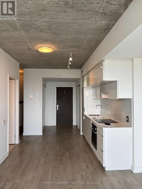 A modern kitchen with white cabinets and a wooden floor.