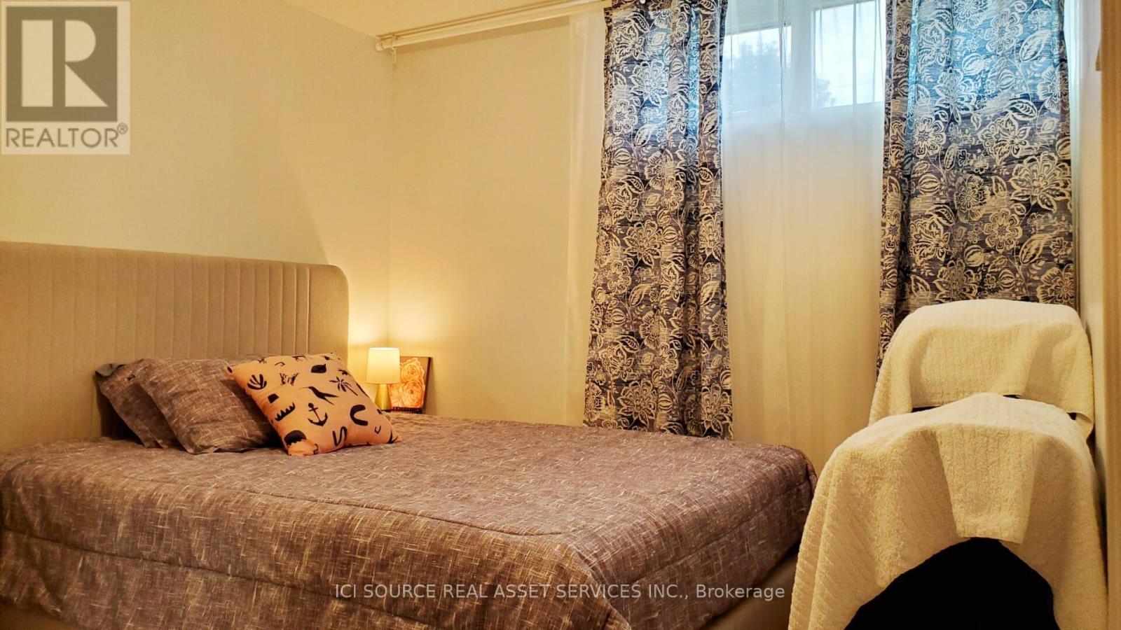 A bedroom with a bed, a lamp, and a chair.
