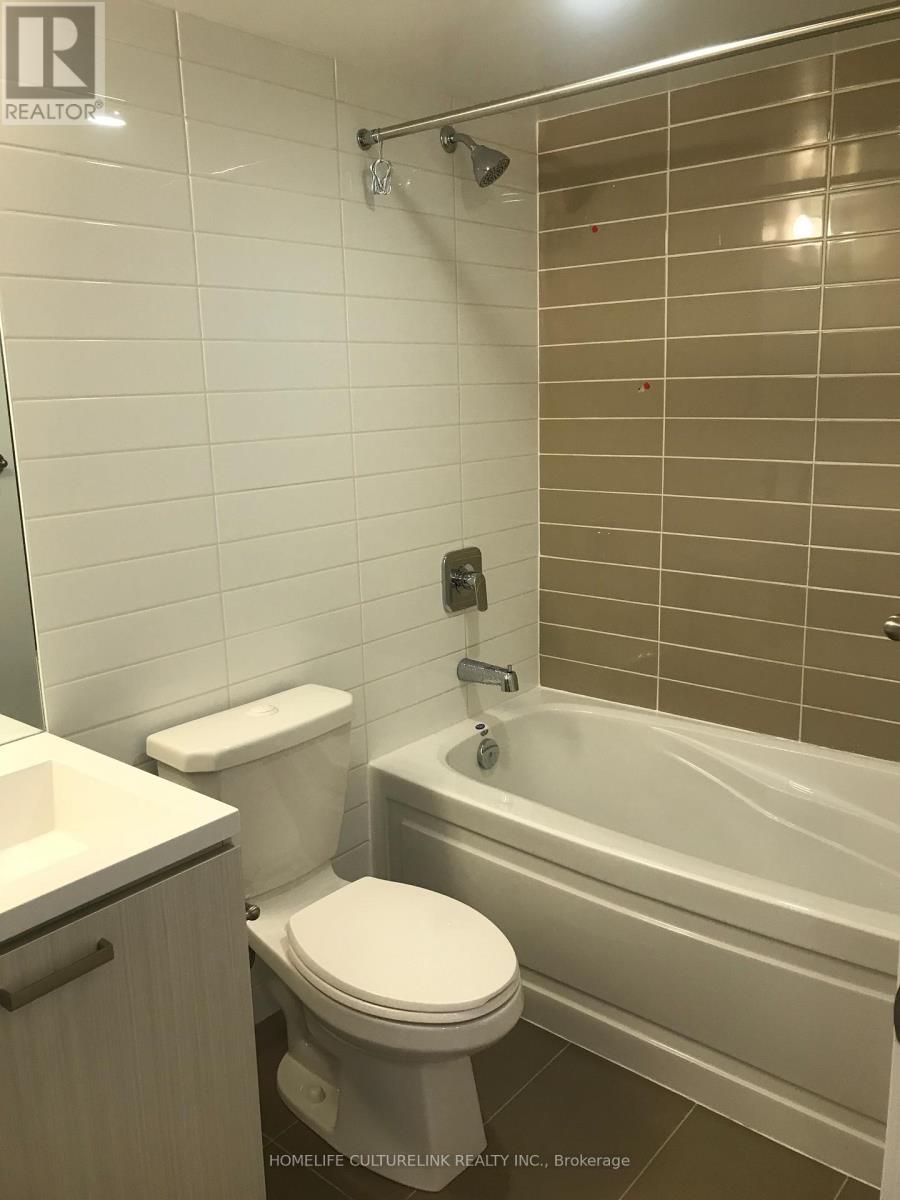 A white toilet sits next to a bathtub in a bathroom.