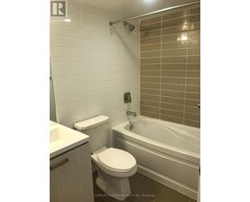 A white toilet sits next to a bathtub in a bathroom.