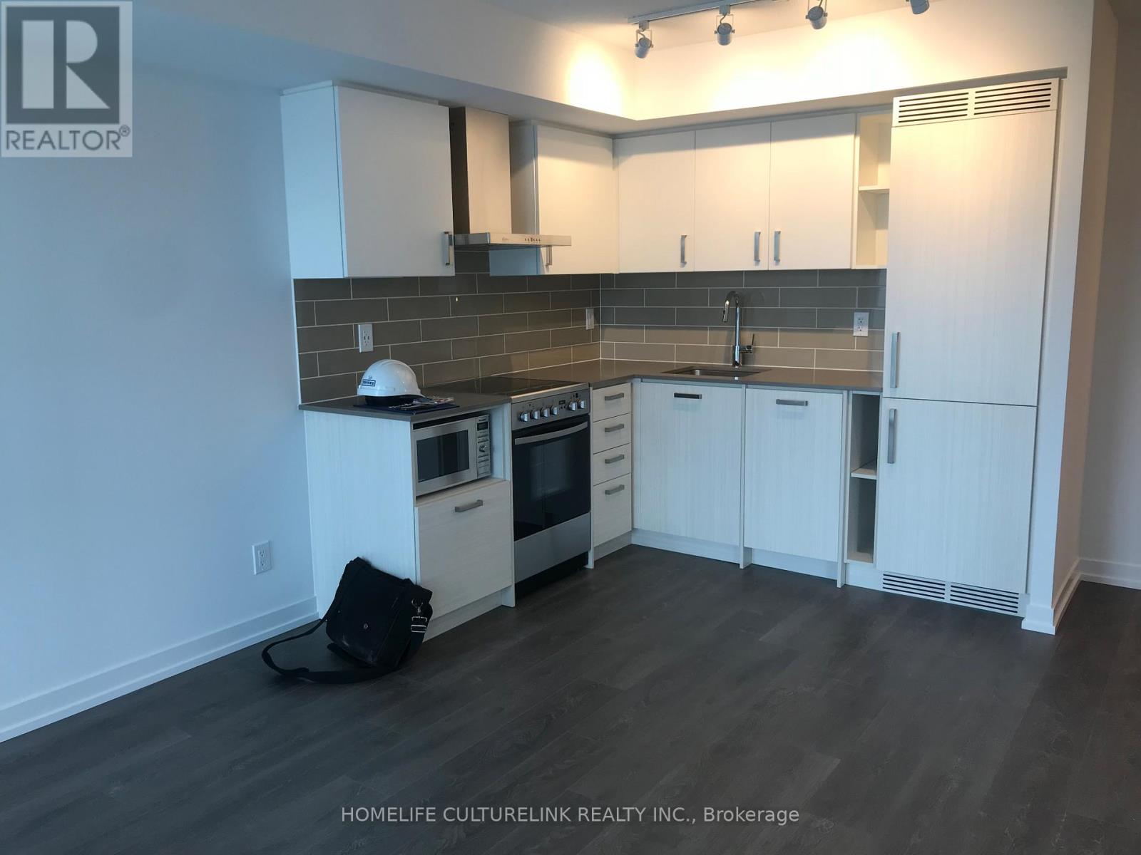 A kitchen with white cabinets and a black bag on the floor.