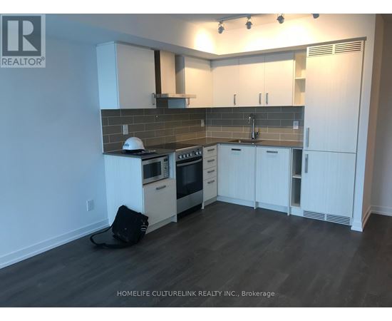 A kitchen with white cabinets and a black bag on the floor.