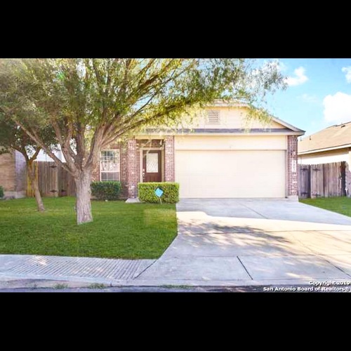 A house with a garage and a tree in front.