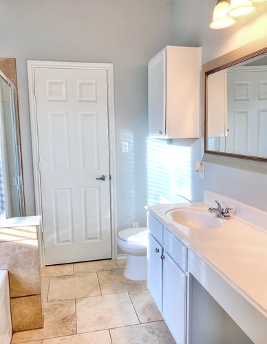 A white bathroom with a toilet, sink, and mirror.