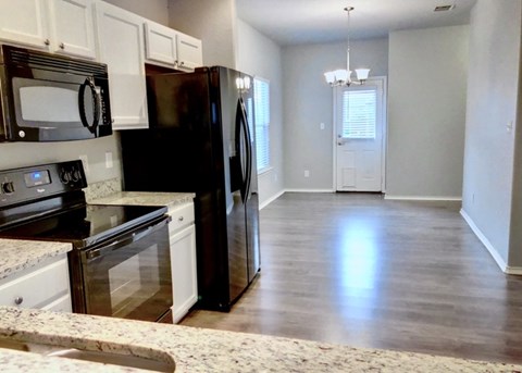A kitchen with black appliances and white cabinets.