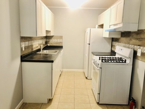 A kitchen with white cabinets and appliances.
