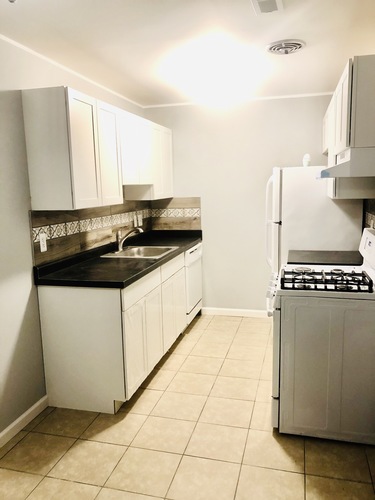 A kitchen with white cabinets and a black countertop.