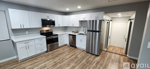 A kitchen with white cabinets and a wooden floor.