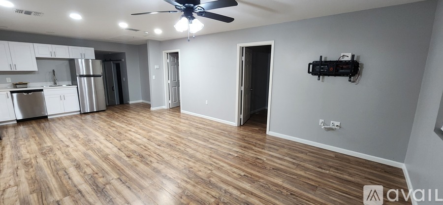 A spacious room with wooden flooring and a ceiling fan.