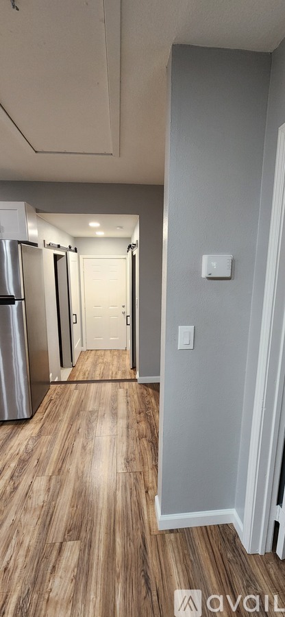 A hallway with wood flooring and white walls.