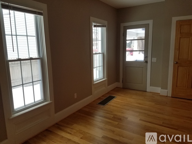A room with wooden floors and two windows.