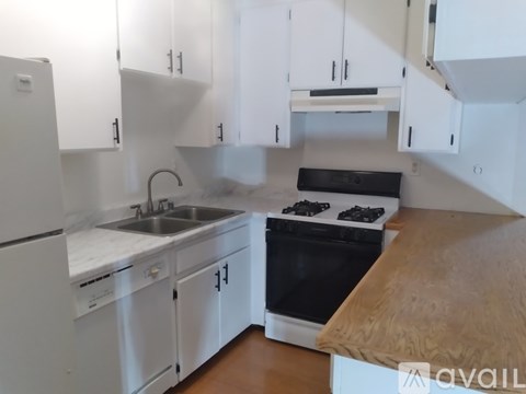 A kitchen with white cabinets and a wooden countertop.