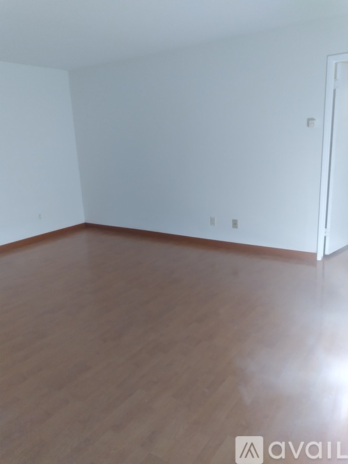 A room with wooden flooring and white walls.