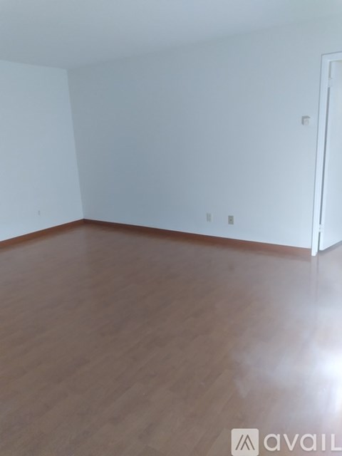 A room with wooden flooring and white walls.