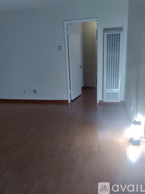 A room with wooden floors and a doorway leading to another room.
