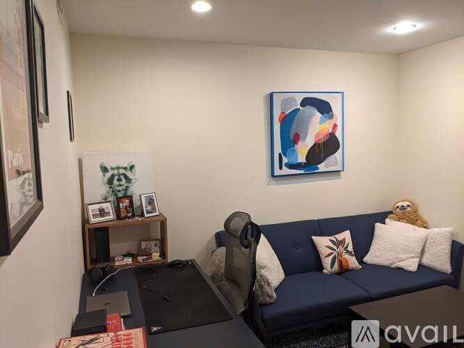 A blue couch with a laptop on a desk in front of it.