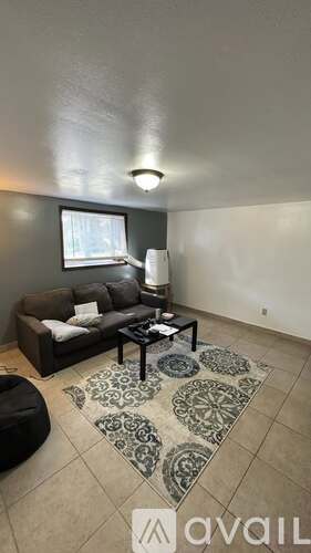 A living room with a couch, coffee table, and rug.