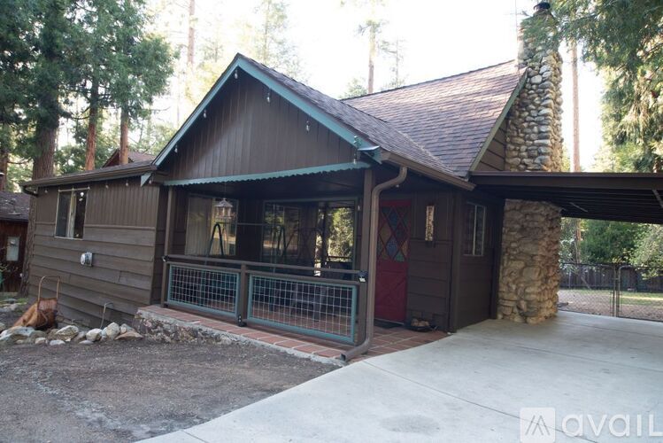 A wooden house with a stone pillar and a red door.