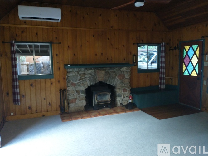 A room with a stone fireplace and wooden walls.