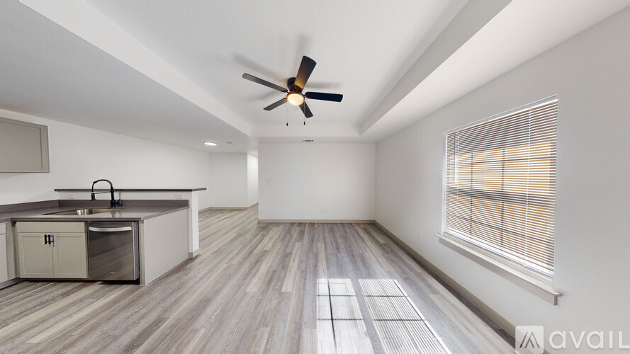A spacious room with a ceiling fan and a window with blinds.