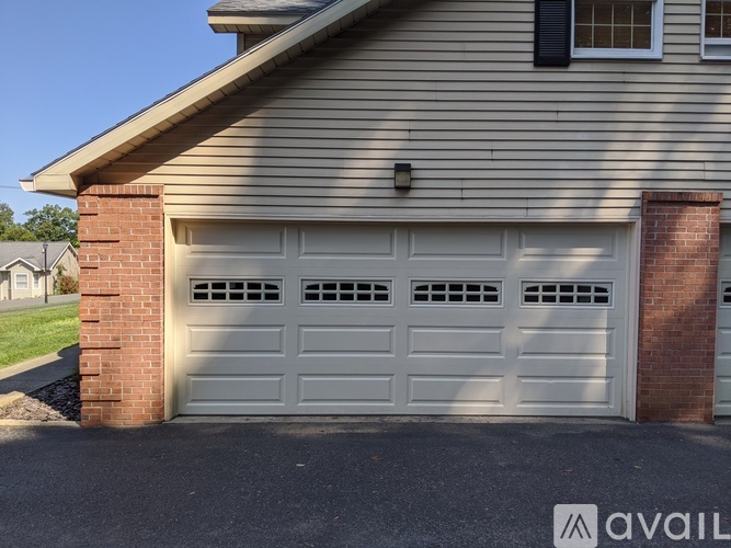 A house with a white garage door and a brick pillar.
