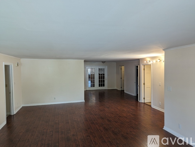 A spacious room with wooden floors and white walls.