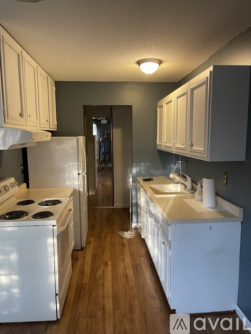A kitchen with white appliances and wooden floors.