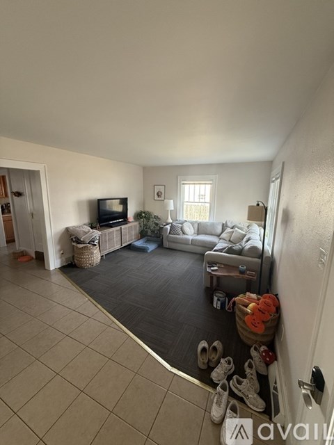A living room with a grey sofa and a television on the left side.