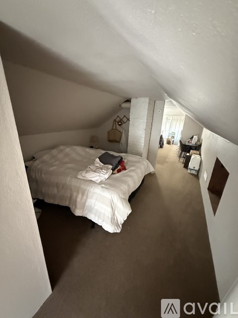 A bedroom with a bed and a couch in the background.