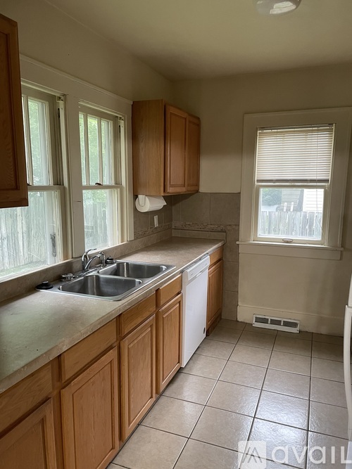 A kitchen with wooden cabinets and a tiled floor.