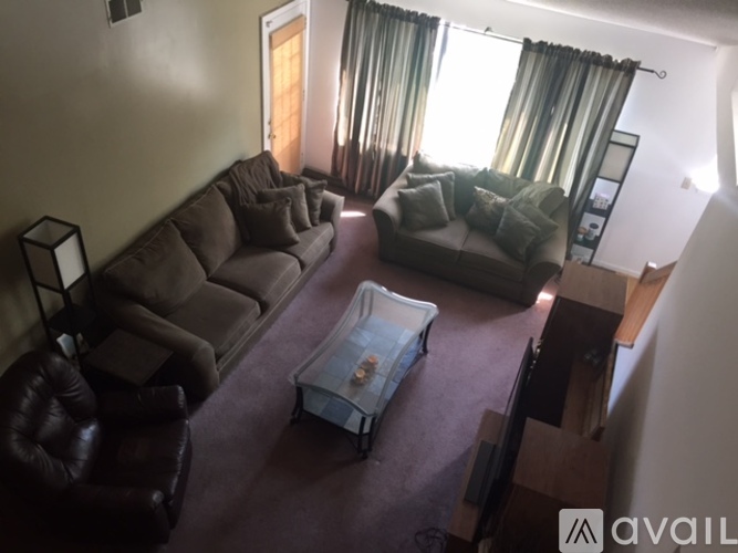 A living room with a brown couch and a glass coffee table.