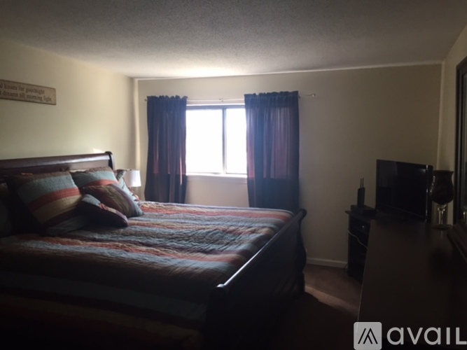 A bedroom with a bed, dresser, and window.