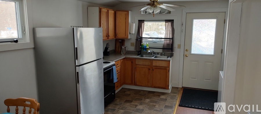 A kitchen with a refrigerator, cabinets, and a ceiling fan.