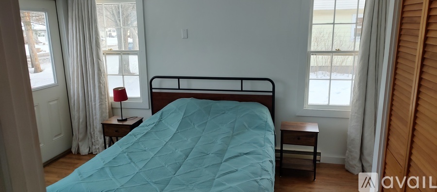 A bedroom with a bed, nightstand, and window.
