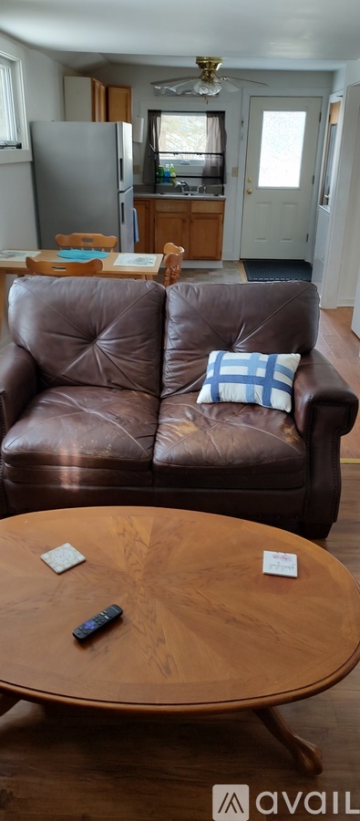 A brown leather couch with a remote control on the table in front of it.