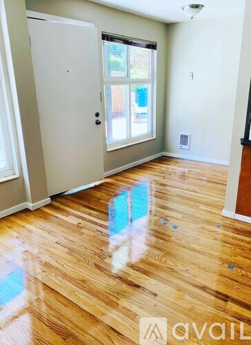 A room with wooden floors and a door leading to a balcony.
