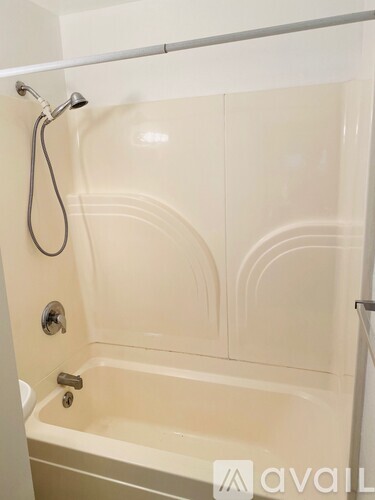 A white bathtub with a shower head and a faucet.