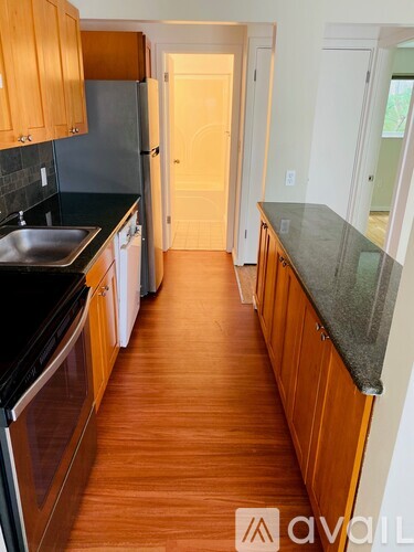 A kitchen with wooden cabinets and a black counter top.