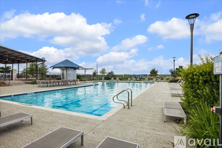 A large outdoor swimming pool with sun loungers and a pavilion.