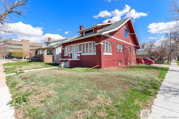 A red house with a white trim and a grey roof.