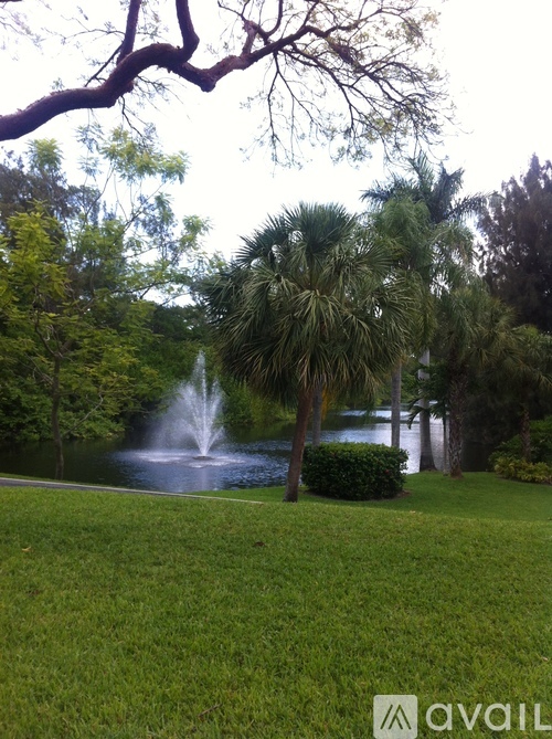 A fountain in the middle of a grassy area surrounded by trees.