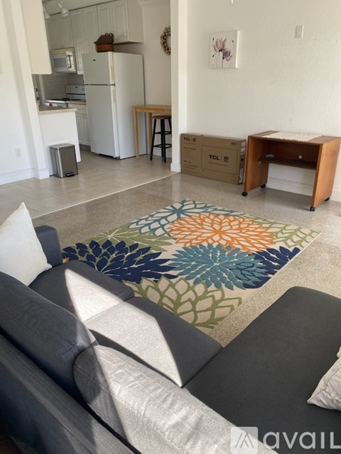 A living room with a grey couch and a rug with a flower design.