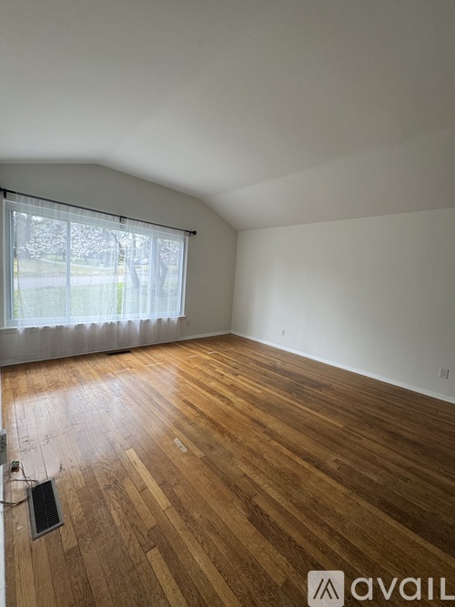 A room with wooden flooring and a window with blinds.