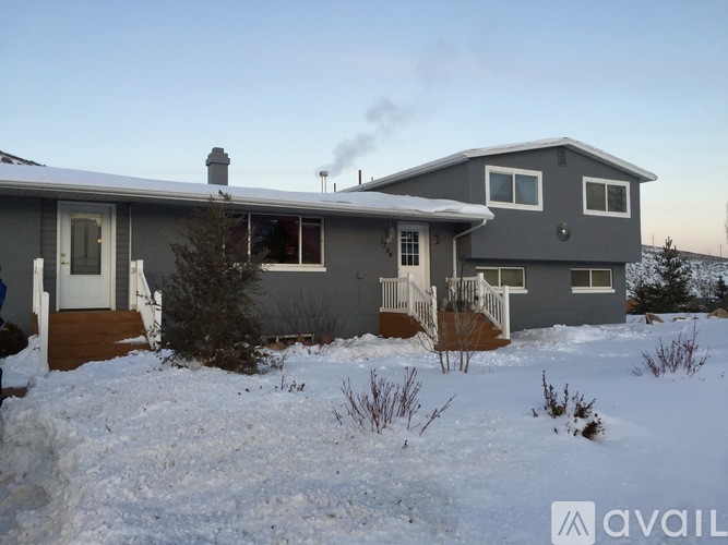 A house with a grey exterior is surrounded by snow.