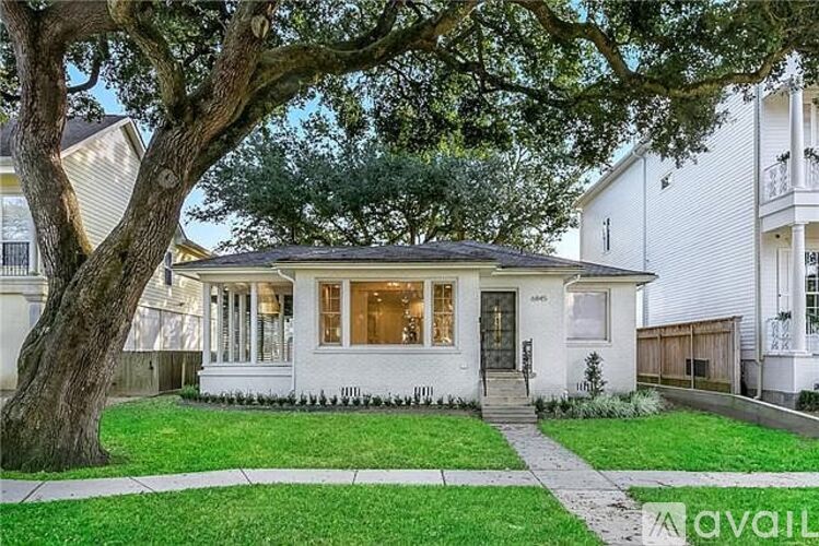 A white house with a tree in front of it.