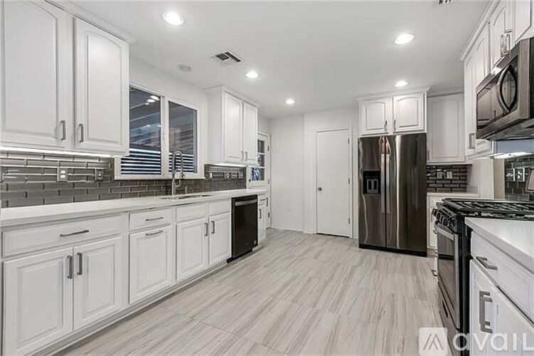 A kitchen with white cabinets and a wooden floor.