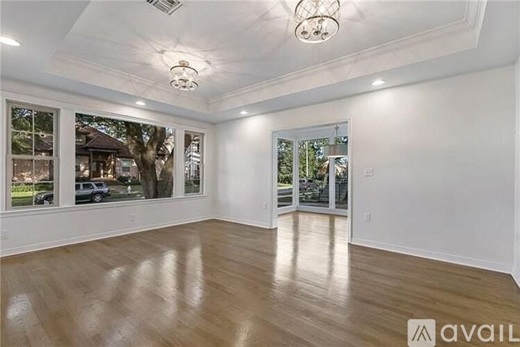 A spacious room with wooden flooring and large windows.