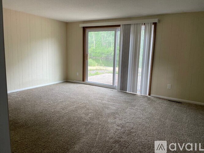 A room with a carpeted floor and a sliding glass door leading to a backyard.